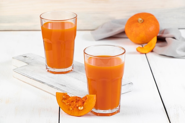 Two glasses of pumpkin juice on white wooden background Vegetable detox drink for healthy diet