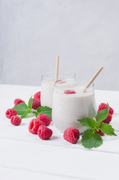 Two glasses of raspberry milkshake on wooden background