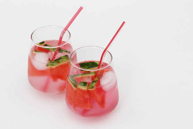 Two glasses of red cocktail with a straw that says'cucumber'on it