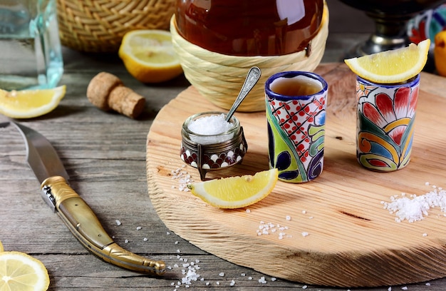 Two glasses of tequila with lemon and salt on a wooden tray