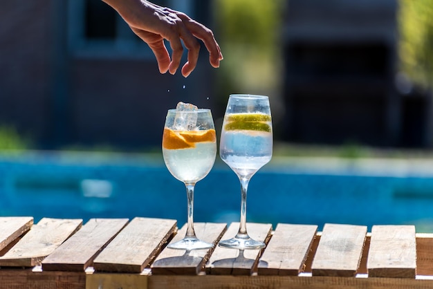 Two glasses of water with a person's hand sprinkling salt on them.