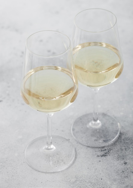 Two glasses of white homemade summer refreshing wine on light stone background