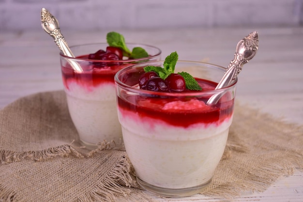 Two glasses of white pudding with a spoon and a mint leaf on top.