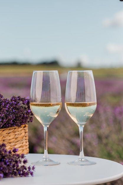 Two Glasses of white wine and bottle in a lavender field in Provance Violet flowers on the background