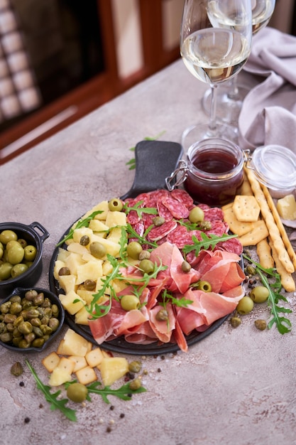 Two glasses of white wine and Italian antipasto meat platter on domestic kitchen