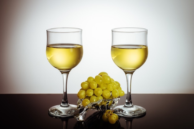 Two glasses of wine and a bunch of grapes on a glass plate