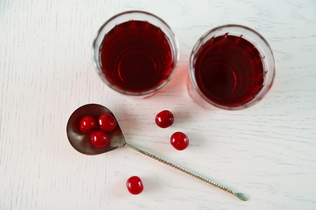 Two glasses with cherry juice on table on light background