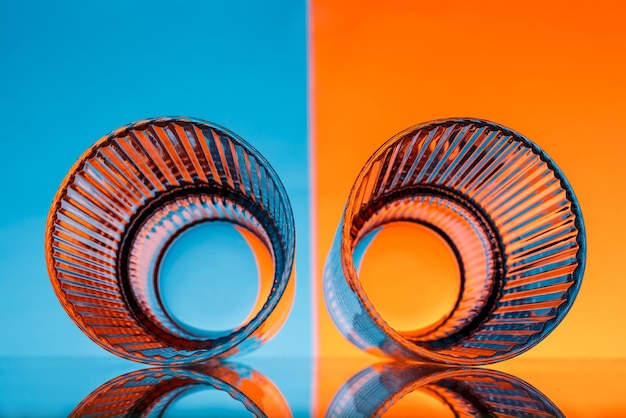 Photo two glasses with water over blue and orange background