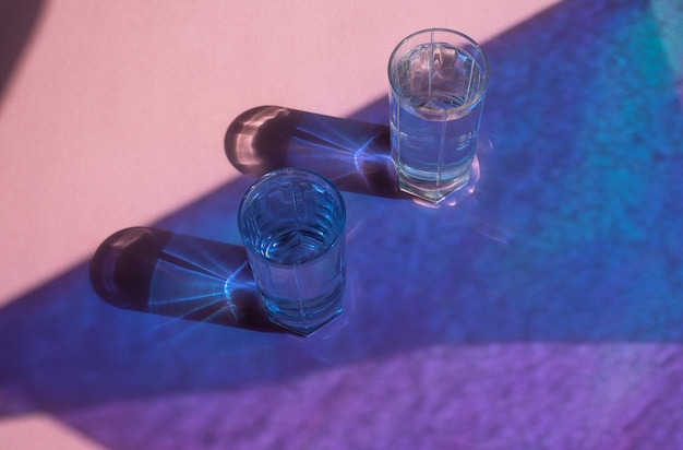 Two glasses with water on a shiny colorful background with highlights and reflections Space for tex