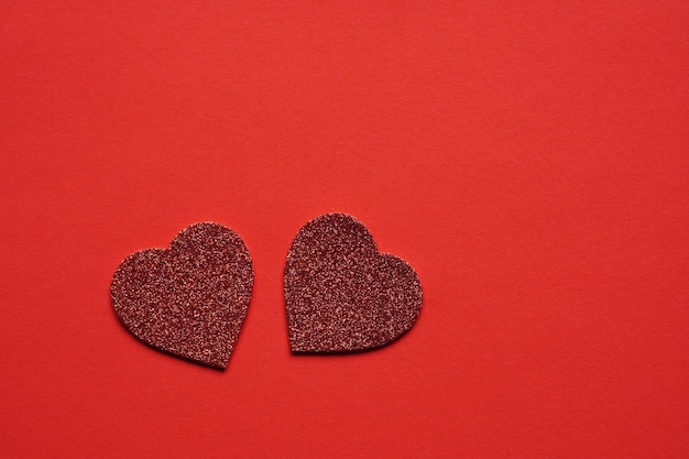 Two glitter hearts on red background