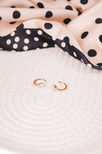 Two gold hoop earrings are on a bed.