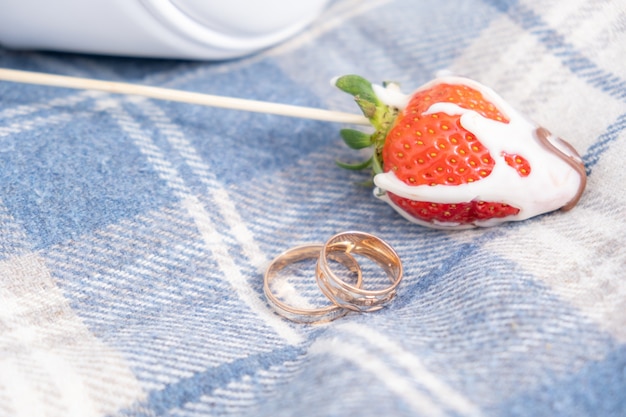 Two gold wedding rings beside strawberry berry, sweet marriage concept, selective focus