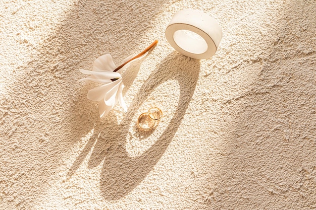 Two gold wedding rings on a relief concrete background among concrete geometric shapes and rays of the sun Concept of wedding background