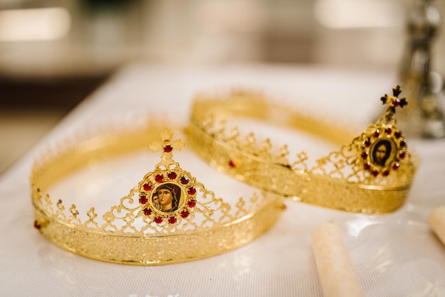 Two golden crown with red gemstones on altar in church traditional wedding ceremony space for text religion Close up