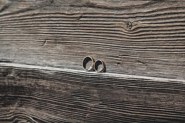 Two golden wedding rings on a piece of wood.