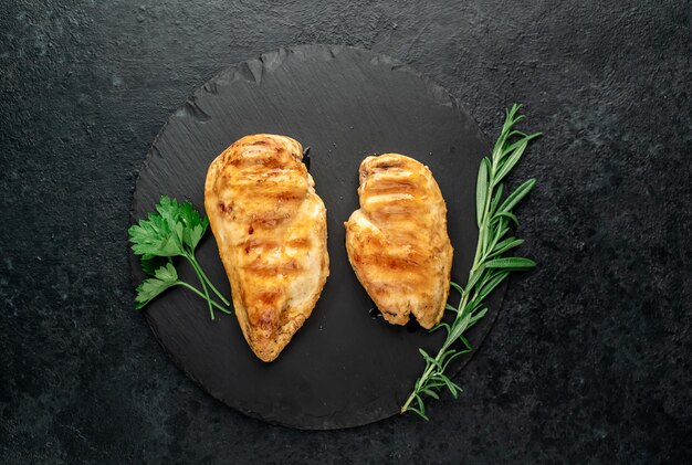 Photo two grilled chicken breasts on a stone background