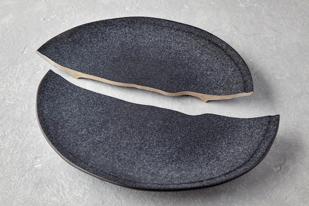 Two halves of a broken dark ceramic plate on a light gray concrete table Division of property in a divorce