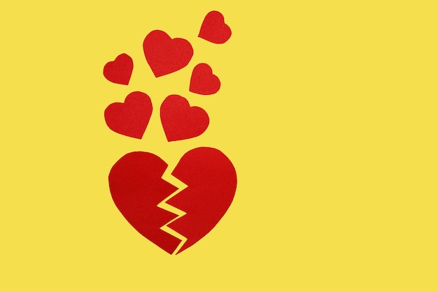 Two halves of a paper heart and small hearts on yellow