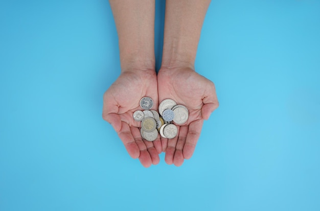 Two hand holding money coin on blue background