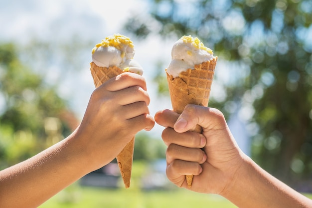 two hands girl holding ice cream cone on summer in light nature background