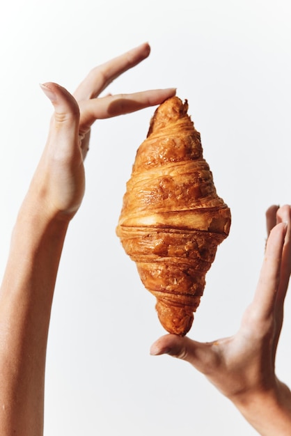 Photo two hands holding a croissant against a white background croissant on top of one hand other hand