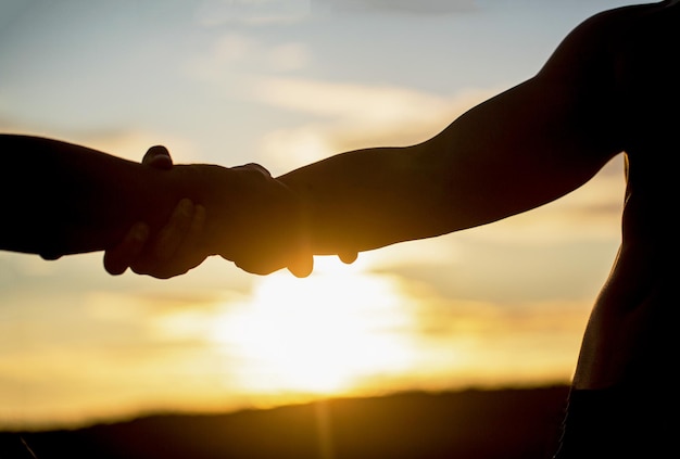 Two hands silhouette on sky background connection or help concept Outstretched hands salvation help silhouette concept help Giving a helping hand Rescue helping gesture or hands