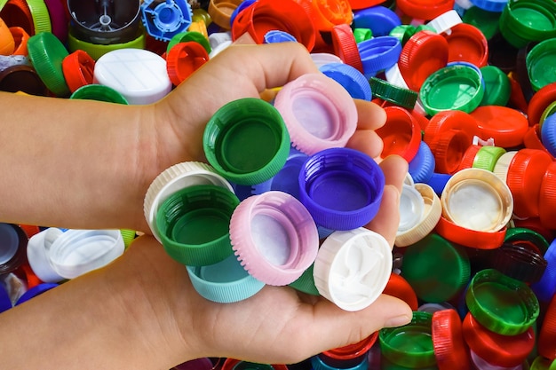 Two hands with plastic caps on the background of plastic caps concept of secondary raw material