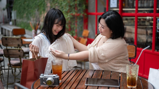 Two happy Asian female friends are enjoying talking while relaxing at an outdoor table