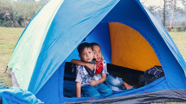 Two happy boys kids inside the tent hugging each other Asian kids Camping ground scene