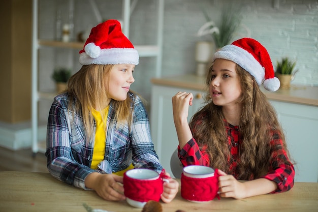 Two happy caucasian girls in red hats in the kitchen