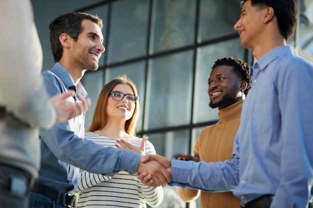 Two happy diverse professional business men executive leaders shaking hands at office meeting