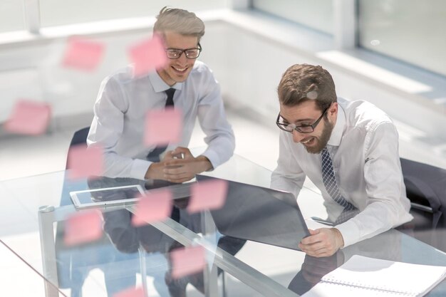 Photo two happy employees reading a business document sitting at a desk in a modern office