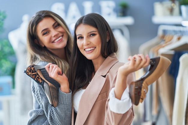 Two happy girls on shopping holding shoes. High quality photo