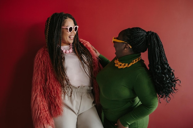 Two happy plus size African woman with braided hair having fun while standing together