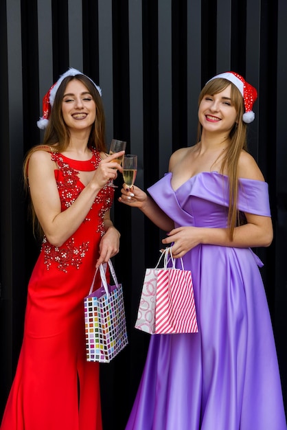 Two happy smiling girls in christmas hats toasting with champagne glasses. New Year and Christmas celebration