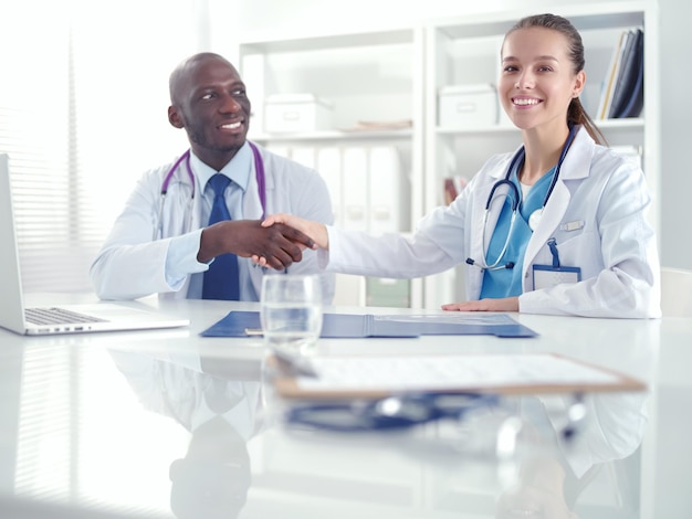 Two happy smiling young medical people handshaking at office Doctors Teamwork