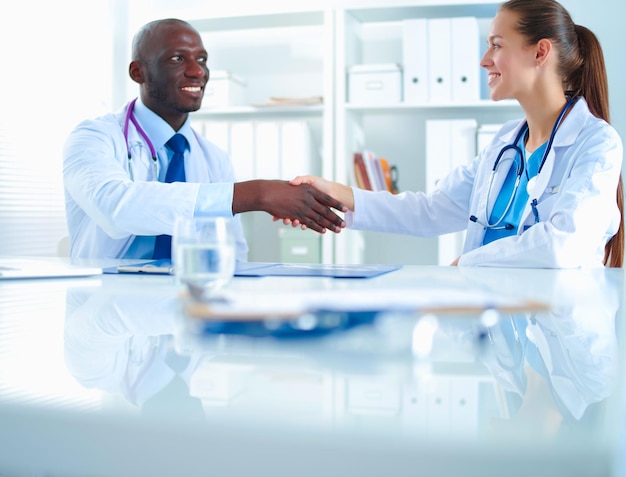 Two happy smiling young medical people handshaking at office