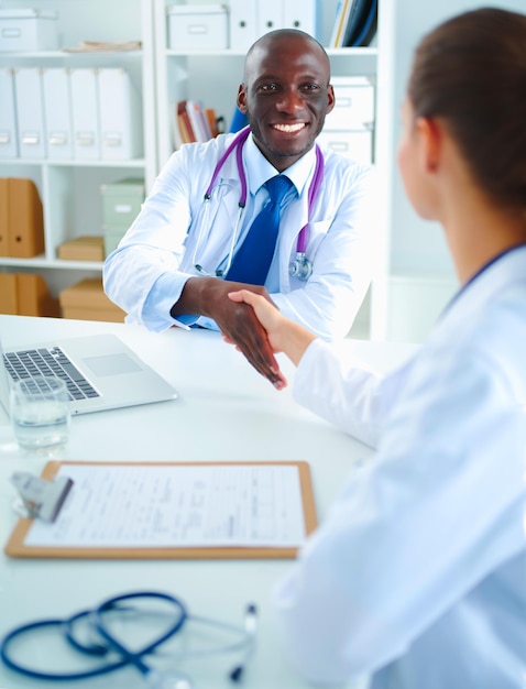 Two happy smiling young medical people handshaking at office