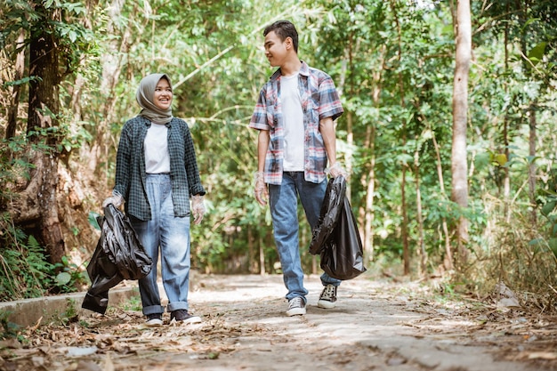 Two happy teenage volunteers picking up trash