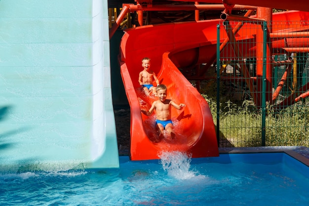 Two happy twin brothers slide down a water slide