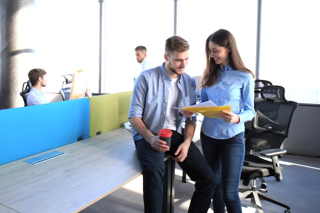 Two happy young people in casual wear smiling and looking at digital tablet while working together.