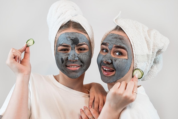 Two happy young woman apply clay mask on face enjoy free time Skincare anti aging treatment