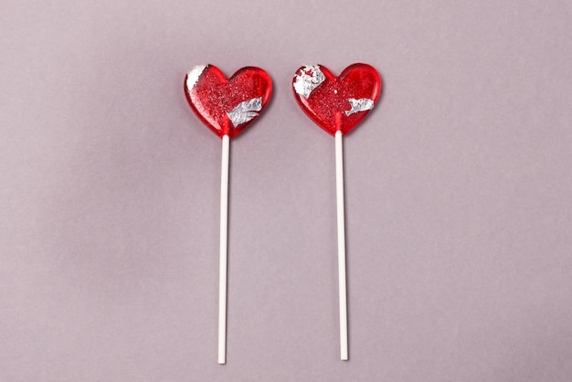 Two Heart Shape Lollipop Candy on Gray Paper Background Love Concept Top View Minimalism Style