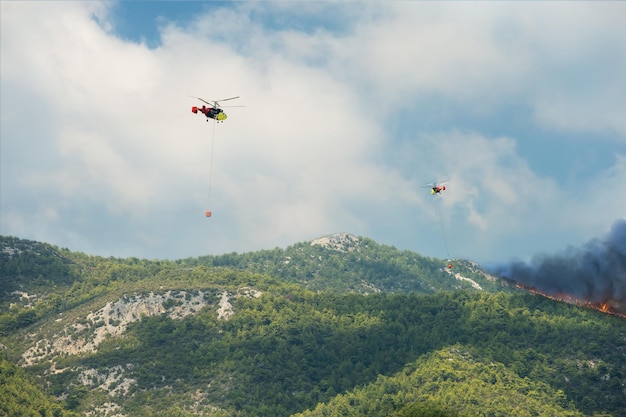 Two helicopters dumping water on forest fire in Mediterranean region