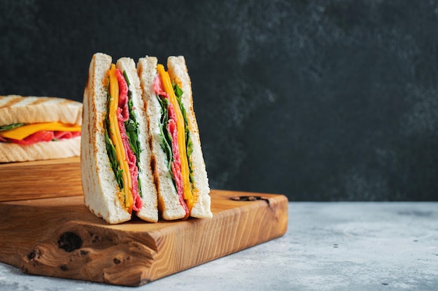 Two homemade sandwiches with sausage cheese and arugula on a light concrete background