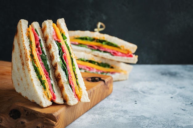 Two homemade sandwiches with sausage cheese and arugula on a light concrete background