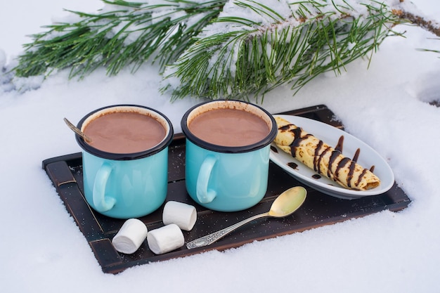 Two hot cocoa drink on a bed of snow and white background close up