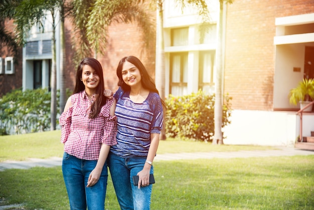 Two Indian asian collage girl students or friends posing for photograph in campus, outdoors