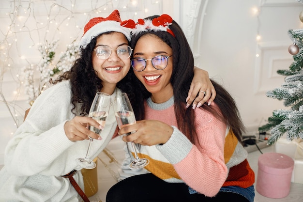 Two indian girl in eyeglasses holding a glassess of champagne