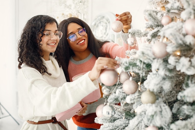 Two indian girls in eyeglasses decorating Christmas tree